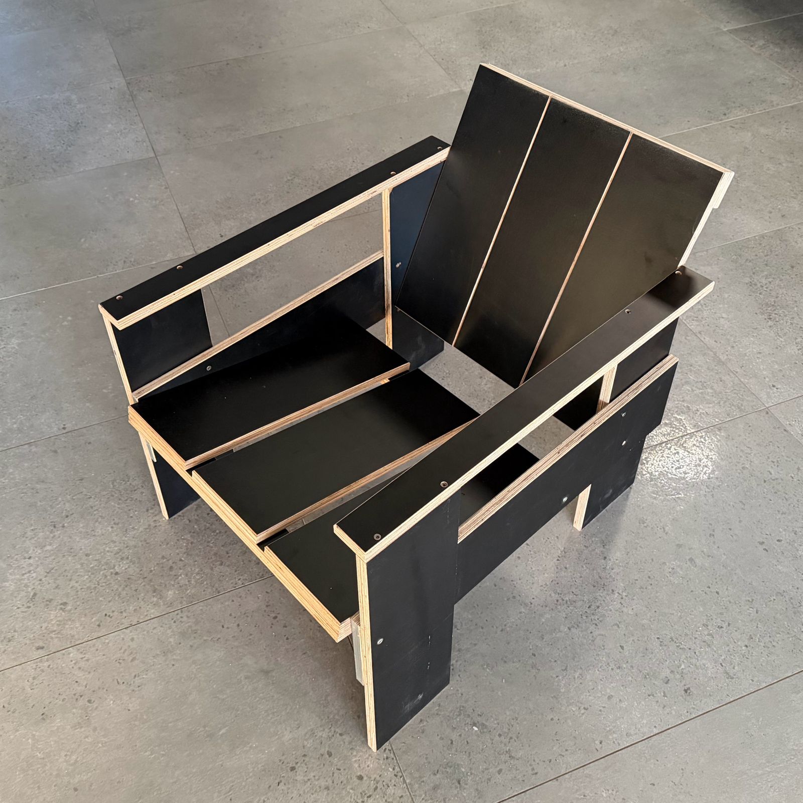 A crate lounge chair built from black film-faced plywood boards, seen from above